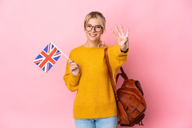 Joven mujer rusa sosteniendo una bandera del Reino Unido aislada sobre fondo rosa feliz y contando cuatro con los dedos