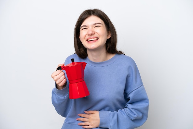 Joven mujer rusa sosteniendo una cafetera aislada de fondo blanco sonriendo mucho