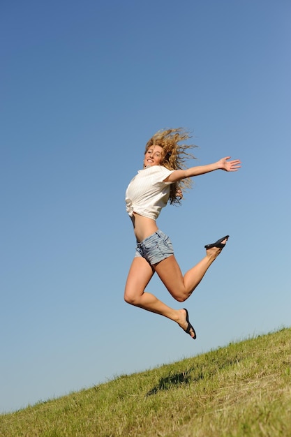 Foto joven mujer saltando en el campo verde de verano