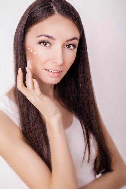 Una joven mujer sana con crema cosmética en un rostro limpio y fresco