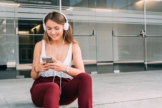 Joven mujer sentada en las escaleras escuchando música en el teléfono móvil