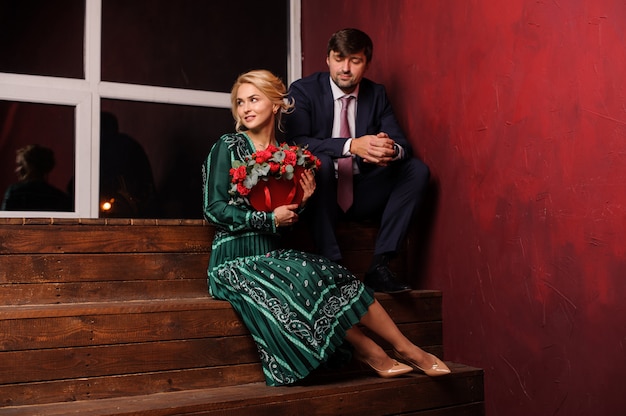 Joven y mujer sentada en las escaleras con el ramo de flores adorables