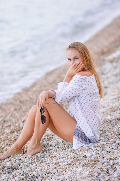 Joven mujer sentada en la orilla del mar