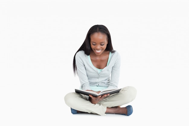 Joven mujer sentada en el piso leyendo un libro