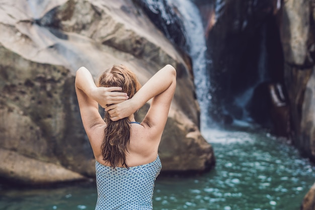 Joven mujer sentada sobre un fondo de cascada