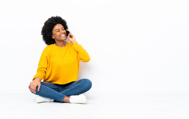 Joven mujer sentada en el suelo manteniendo una conversación con el teléfono móvil