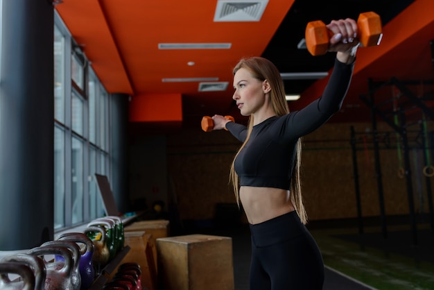 Joven mujer sexy durante el entrenamiento de fitness en el gimnasio