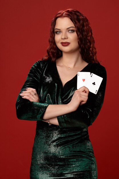 Joven mujer sexy con un pelo rizado rojo con ases, sobre un fondo rojo. Póker