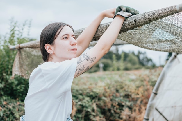 Joven mujer sonriente descansando con una gran sonrisa en su rostro al aire libre en un invernadero después de la recolección estacional de verduras feliz después de un día de trabajo Imagen divertida de recolección rural