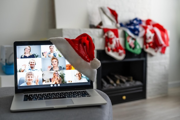 Una joven mujer sonriente con sombrero rojo de Santa Claus haciendo videollamadas en la red social con familiares y amigos el día de Navidad.