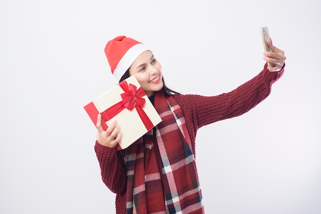 Una joven mujer sonriente con sombrero rojo de Santa Claus tomando un selfie en blanco