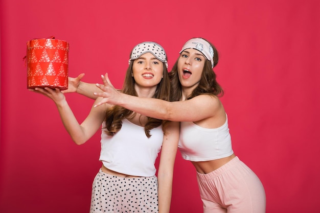 Foto joven mujer sorprendida sosteniendo un regalo mientras celebraba un cumpleaños con su amiga