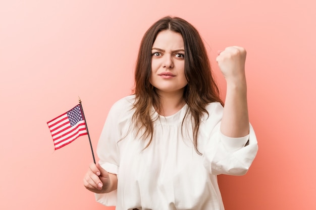 Joven mujer sosteniendo una bandera de Estados Unidos mostrando el puño