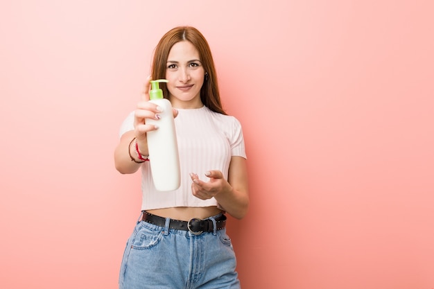 Joven mujer sosteniendo una botella de crema