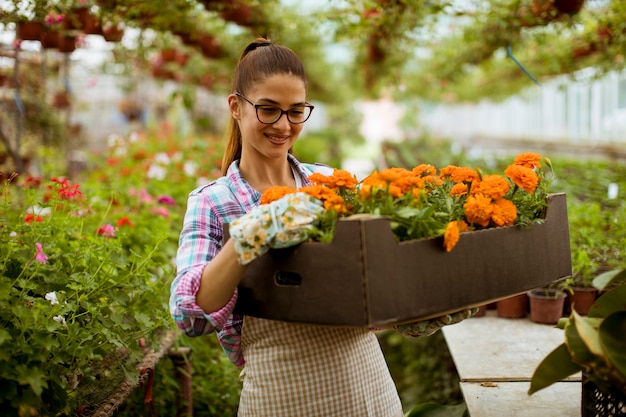 Joven mujer sosteniendo una caja llena de flores de primavera