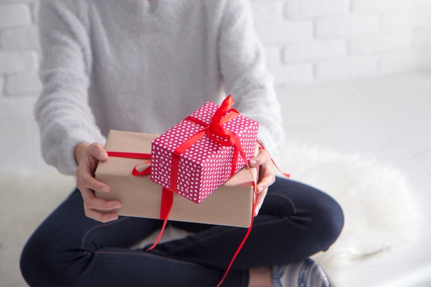 joven mujer sosteniendo una caja de regalo con cinta roja.