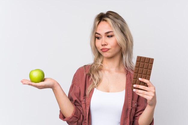 Joven mujer sosteniendo un chocolate y manzana