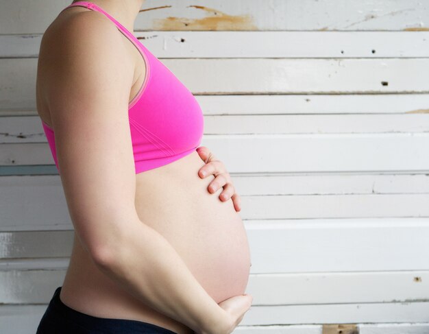 Joven mujer sosteniendo estómago embarazada