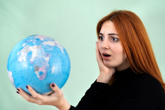 Foto joven mujer sosteniendo un globo geográfico en su mano