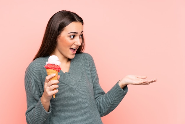 Joven mujer sosteniendo un helado de cucurucho en rosa con expresión facial sorpresa
