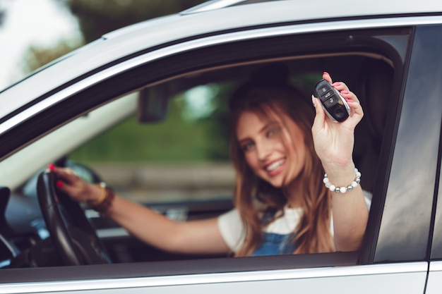 Joven mujer sosteniendo las llaves de coche nuevo