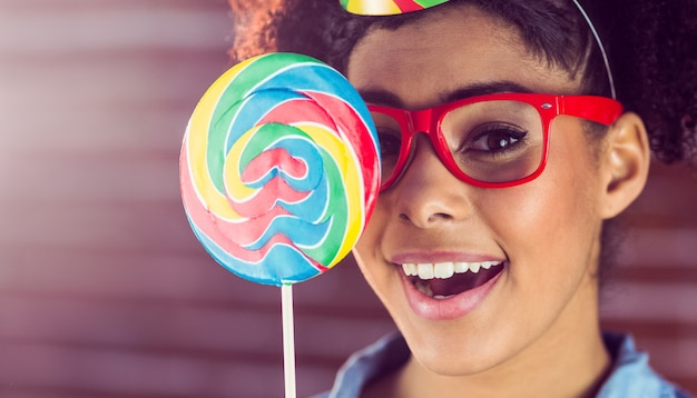 Foto joven mujer sosteniendo una paleta contra su cara