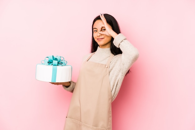 Joven mujer sosteniendo un pastel guardando un secreto o pidiendo silencio.