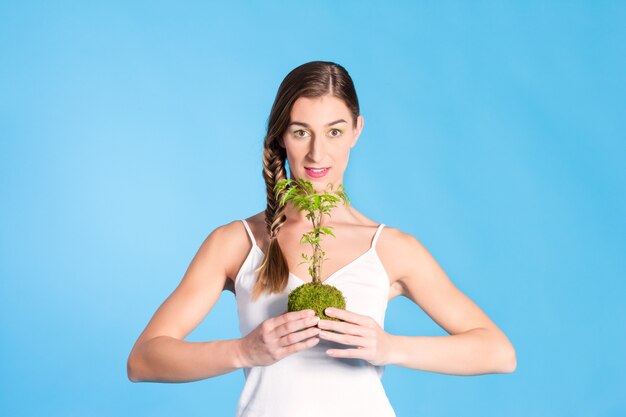 Joven mujer sosteniendo un pequeño árbol