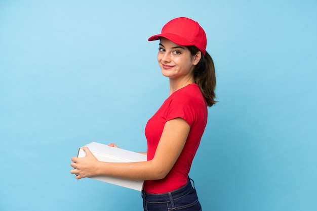 Joven mujer sosteniendo una pizza sobre pared rosa aislado riendo