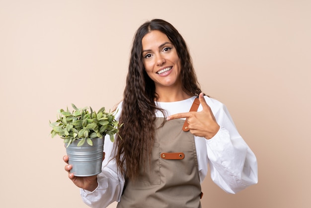 Joven mujer sosteniendo una planta y apuntando