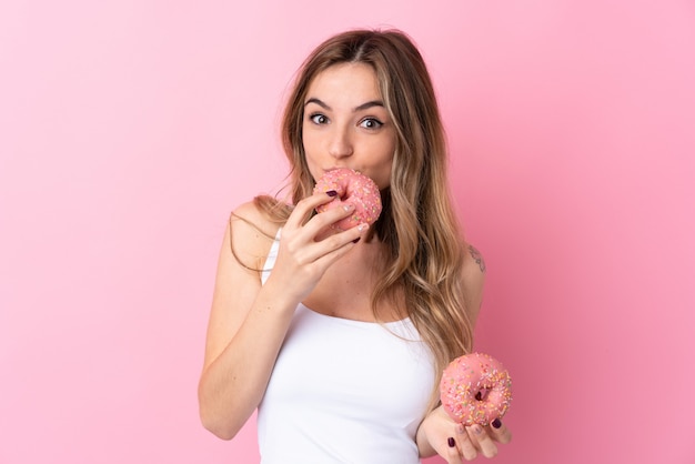 Joven mujer sosteniendo una rosquilla sobre pared aislada