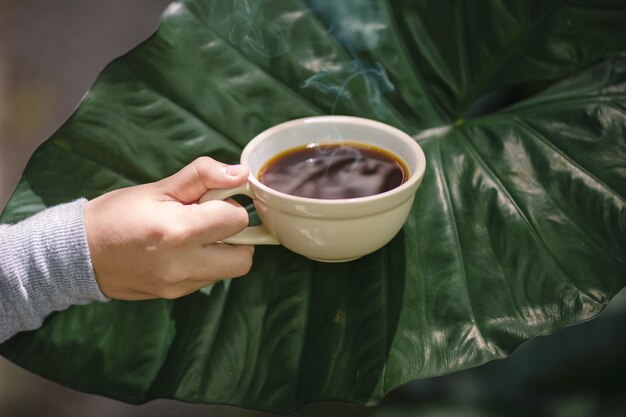 Joven mujer sosteniendo una taza de café caliente en vista de la naturaleza