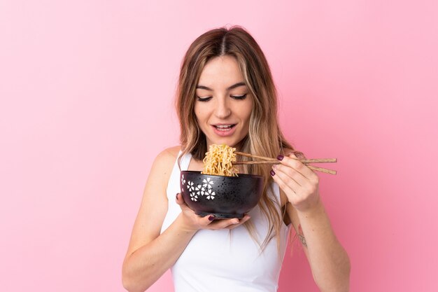 Joven mujer sosteniendo un tazón de fideos con palillos