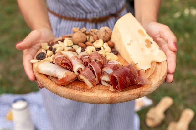 Joven mujer sostiene un plato de madera con delicias de carne.