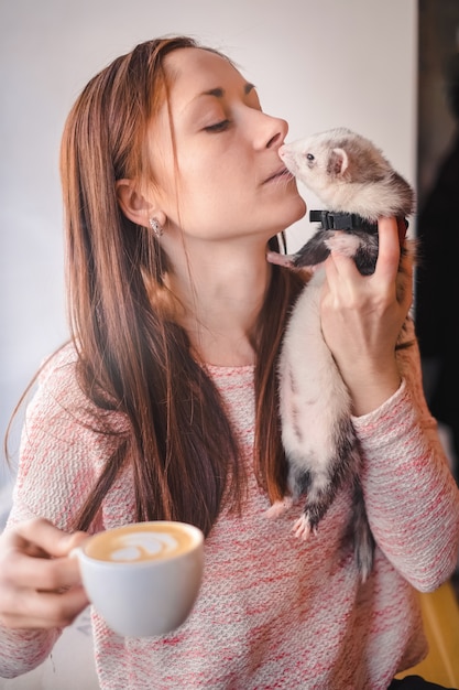 Joven mujer y su mascota hurón en café