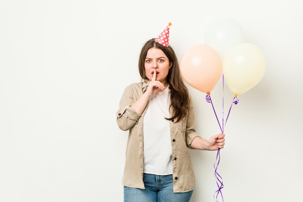 Joven mujer de talla grande con curvas celebrando un cumpleaños guardando un secreto o pidiendo silencio.