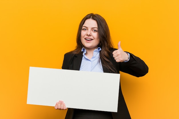 Foto joven mujer de talla grande con curvas sosteniendo un cartel sonriendo y levantando el pulgar hacia arriba