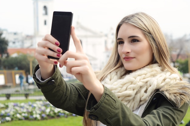 Joven mujer tomando selfie con su teléfono inteligente.