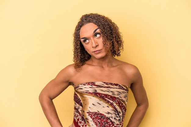 Foto joven mujer transexual latina aislada de fondo amarillo confundida, se siente dudosa e insegura.