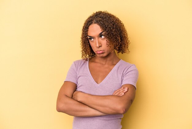 Joven mujer transexual latina aislada sobre fondo amarillo cansada de una tarea repetitiva.