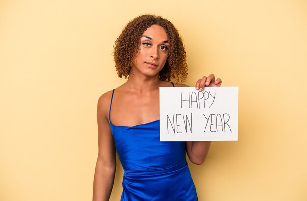 Joven mujer transexual latina celebrando el año nuevo aislado sobre fondo amarillo feliz, sonriente y alegre.