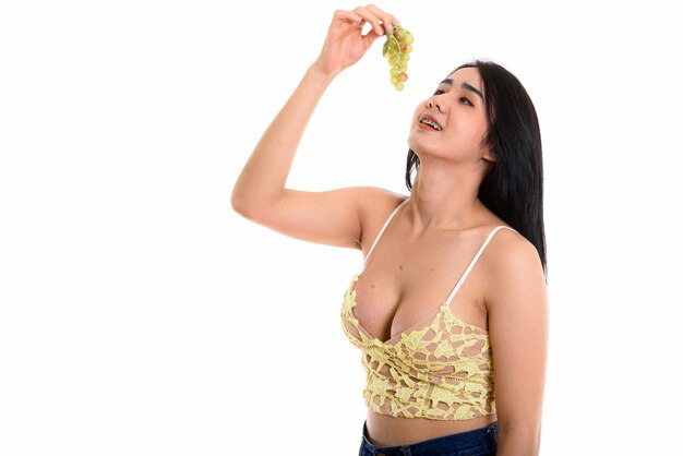 Joven mujer transgénero asiática feliz sonriendo mientras come uvas