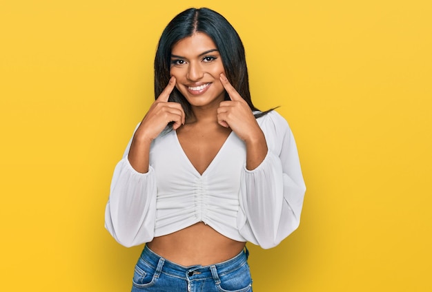 Foto joven mujer transgénero transexual latina con ropa informal sonriendo con la boca abierta, señalando con los dedos y forzando una sonrisa alegre