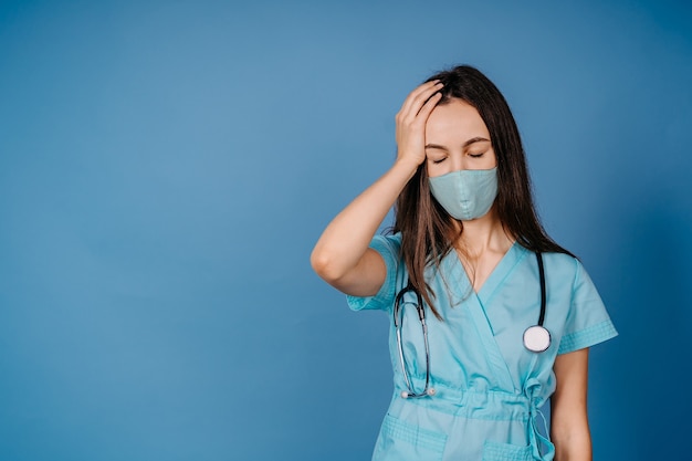 Joven mujer triste caucásica Reino Unido EE. UU. NHS EMS médico ojos cerrados con mascarilla esperanza fe en la superación de la crisis pandémica del coronavirus COVID-19