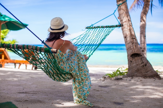 Joven mujer tumbada en la hamaca en la playa tropical