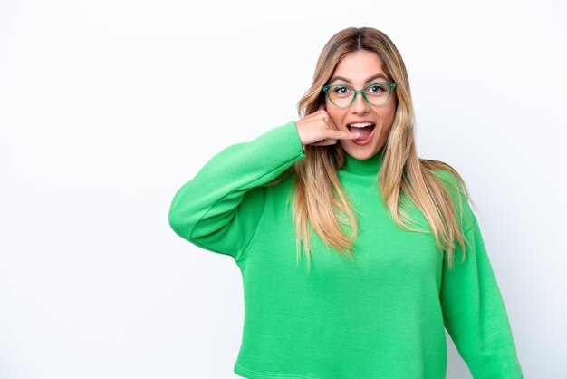 Joven mujer uruguaya aislada sobre fondo blanco haciendo gesto de teléfono Llámame de nuevo firmar