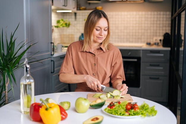 Joven mujer vegetariana sonriente preparando comida vegana saludable sola en casa Chica en forma atractiva preparar una cena saludable hacer sorpresa para el marido Concepto de estilo de vida de comida saludable