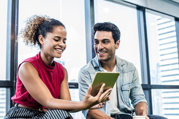 Joven y mujer viendo tableta digital en oficina moderna y feliz