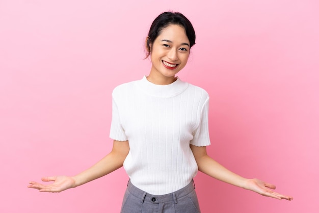 Joven mujer vietnamita aislada sobre fondo rosa con dudas