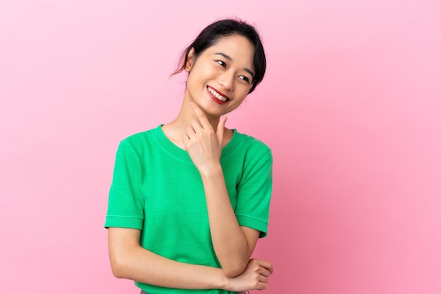 Joven mujer vietnamita aislada sobre fondo rosa feliz y sonriente